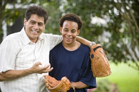 A teenager and his stepfather play catch outside.