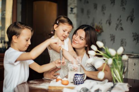 A mother and her children prepare a meal together at their kitchen table.