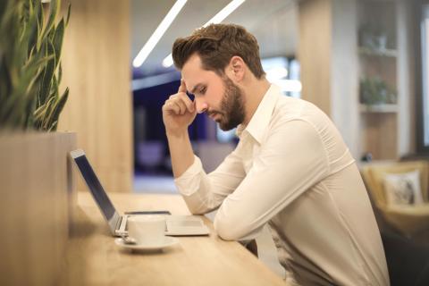 Man looks over his computer with a stressful expression.