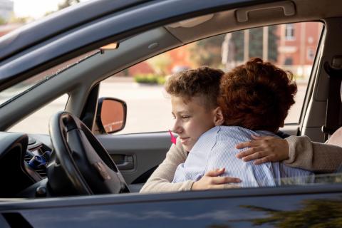 Mom hugging son in car.