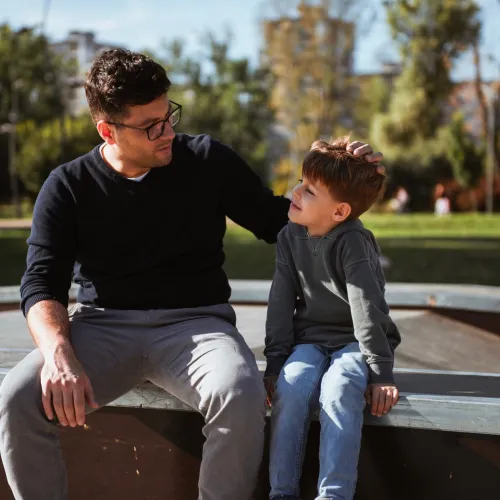 Dad having serious discussion with son on bench. 