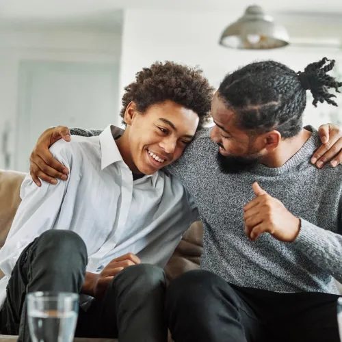 Dad and son on couch talking happily.