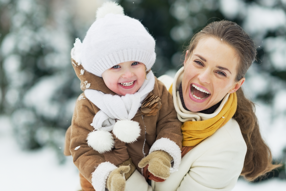 Bundled up, smiling mom and child playing outside during the winter