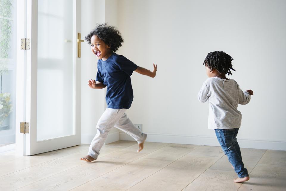 Younger brother chases older sibling around living room while playing