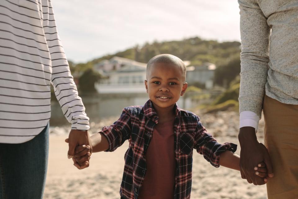 A boy holds the hands of his parents.