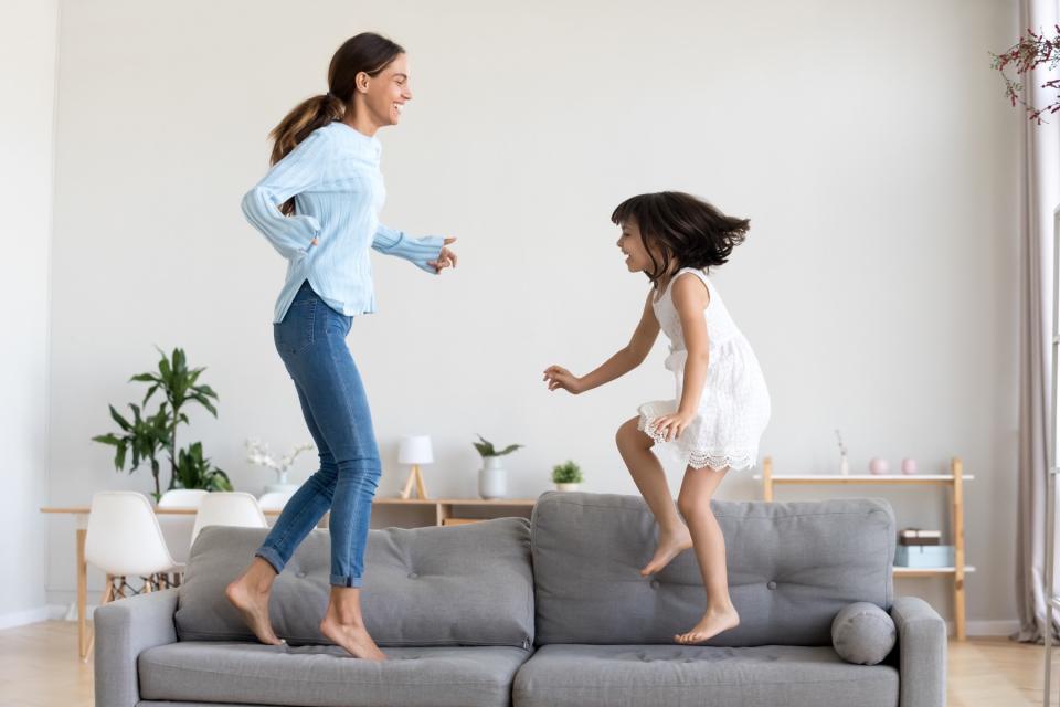 A girl and her mother play together in the living room.