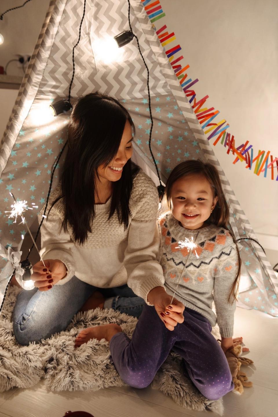 Mother and daughter celebrate a holiday together and play with sparklers.