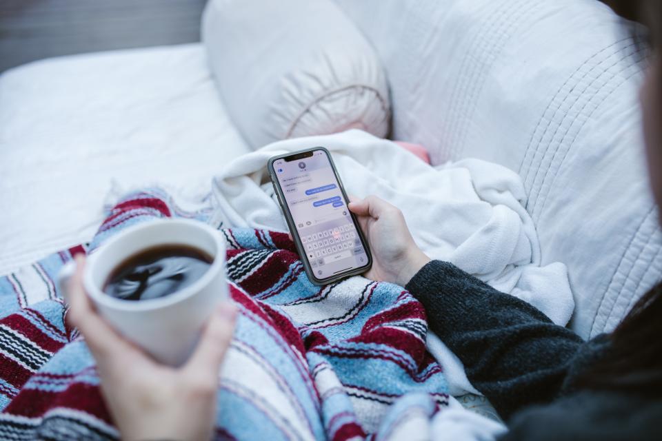 photo of phone in hand with coffee in other hand