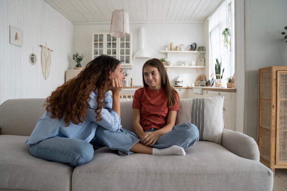 A mother and daughter have a discussion while sitting on a couch.
