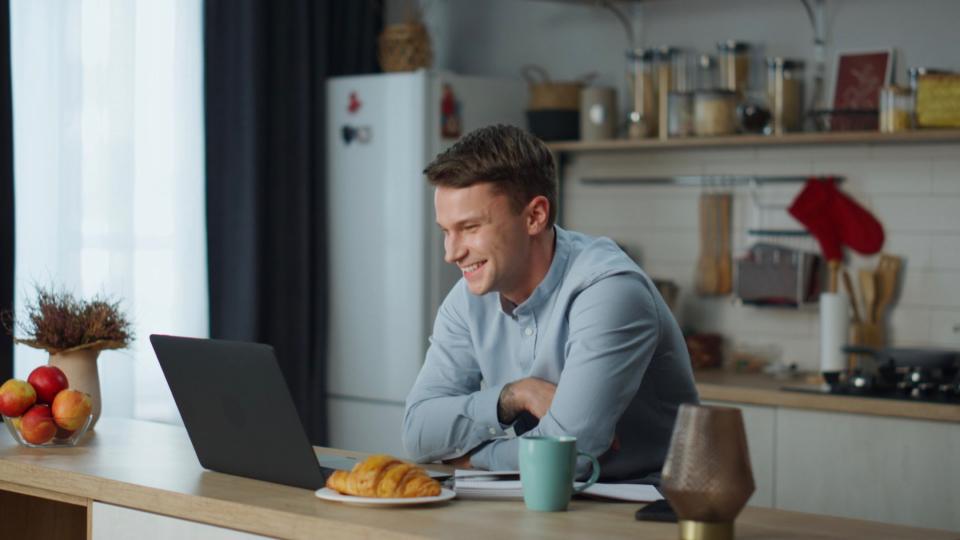 Man on laptop in kitchen.