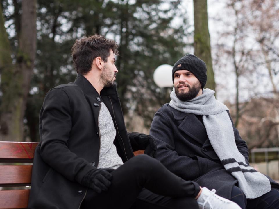 Two men talking seriously on bench. 