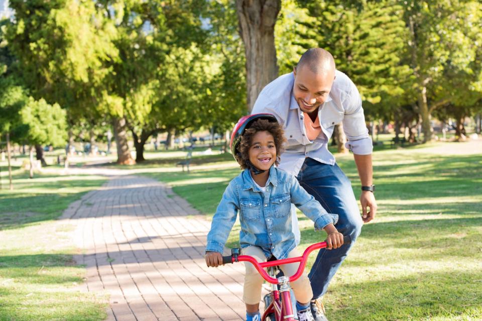 Dad teaching daughter how to ride a bike.